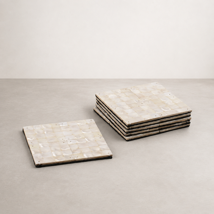 Mother of pearl coasters, one laid flat beside a stack of five shell-tiled squares