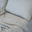 Rumpled pencil-stripe French linen bedding, fine woven stripes over a pale ground
