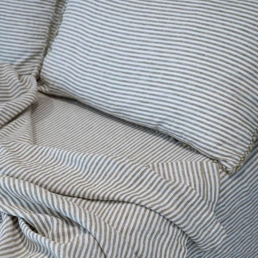 Rumpled pencil-stripe French linen bedding, fine woven stripes over a pale ground
