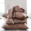 Tabako Linen Cushion — stack of textured tobacco linen cushions with frayed edges