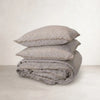 Pencil-stripe linen pillowcases stacked on a folded quilt cover in matching stripe