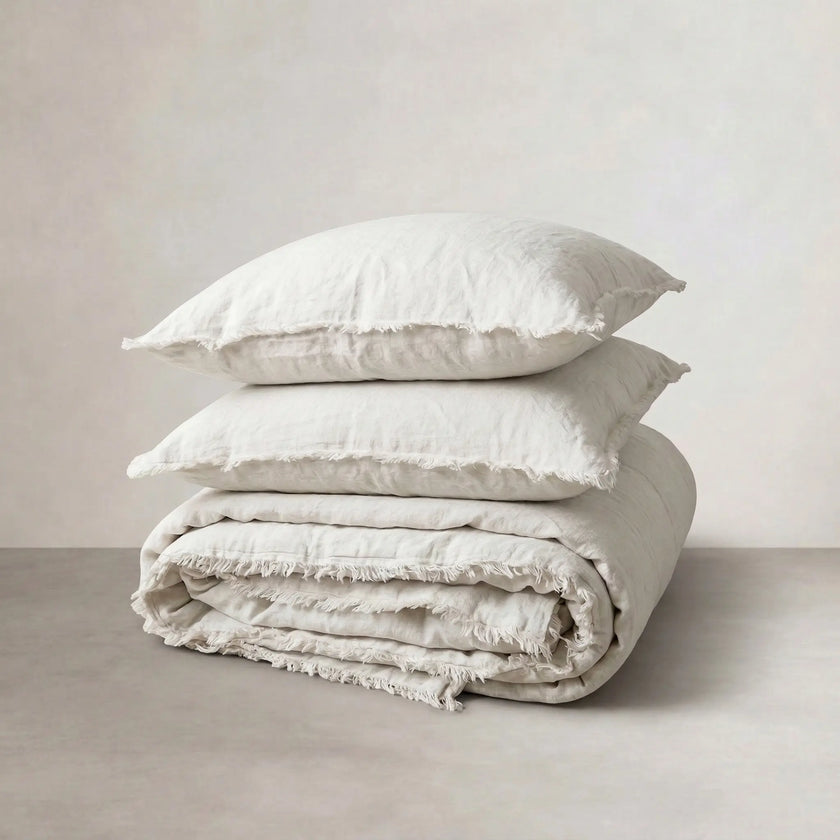 Folded off-white linen quilt cover topped with a pair of matching pillowcases