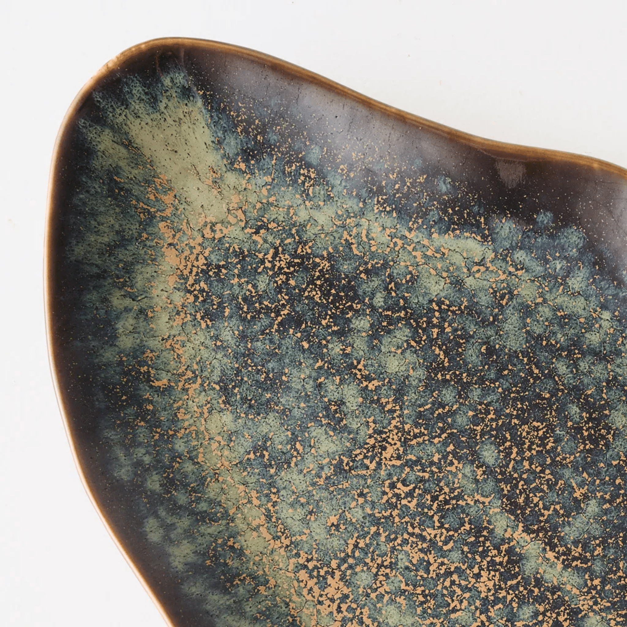 Close view of a Tova plate, reactive glaze pooling in moss and latte over espresso